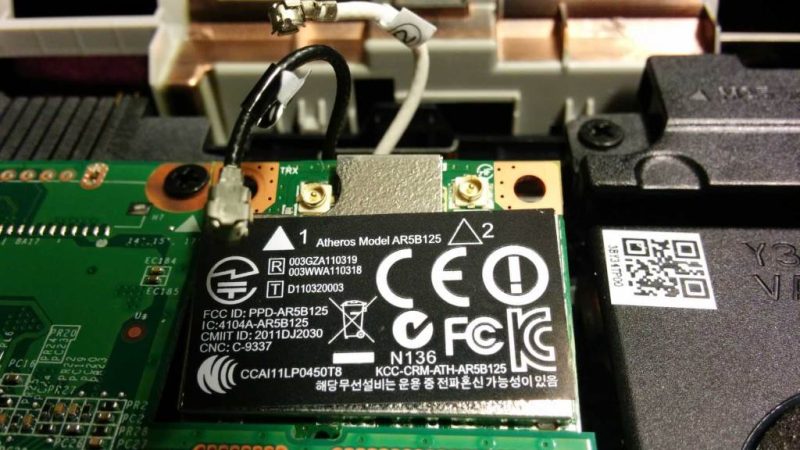 Close-up of a WiFi card installed in a laptop motherboard showing signal drop indicators on screen.