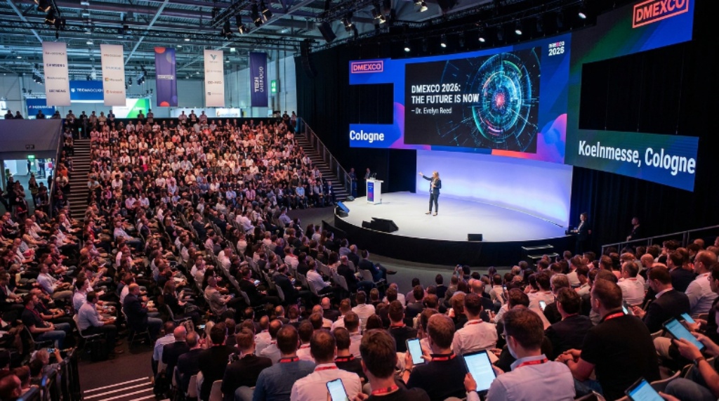 A packed conference stage at DMEXCO 2026 in Cologne, with a keynote speaker presenting to thousands of digital marketing and technology professionals